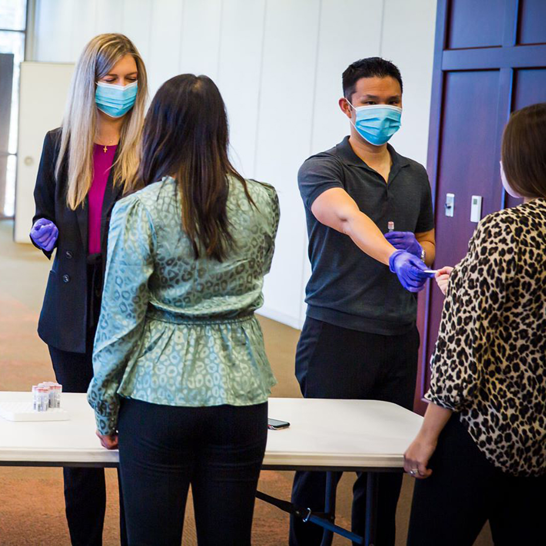 Image of masked NuStar employees handing out band-aids in preparation of the on-site COVID-19 vaccination. 
